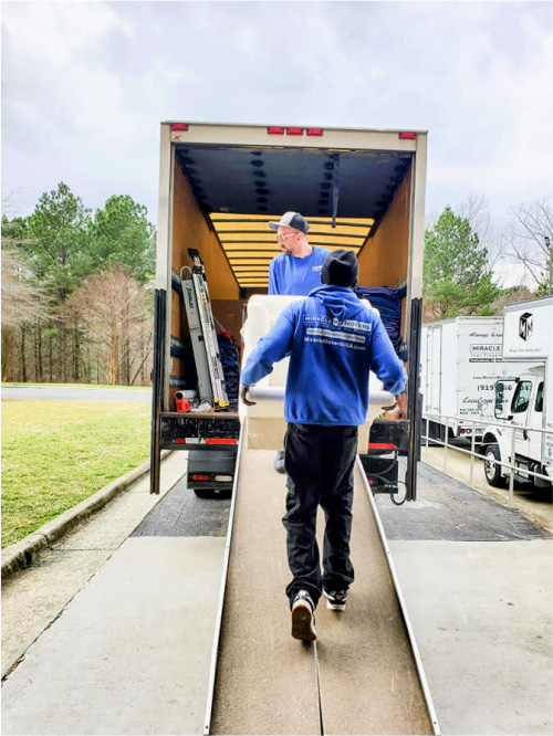 An image of Two members of Miracle Movers loading items into the truck